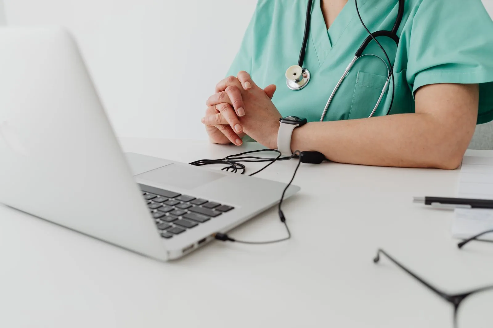 Professionista medico in divisa che utilizza un laptop per consultazioni a distanza e documentazione.