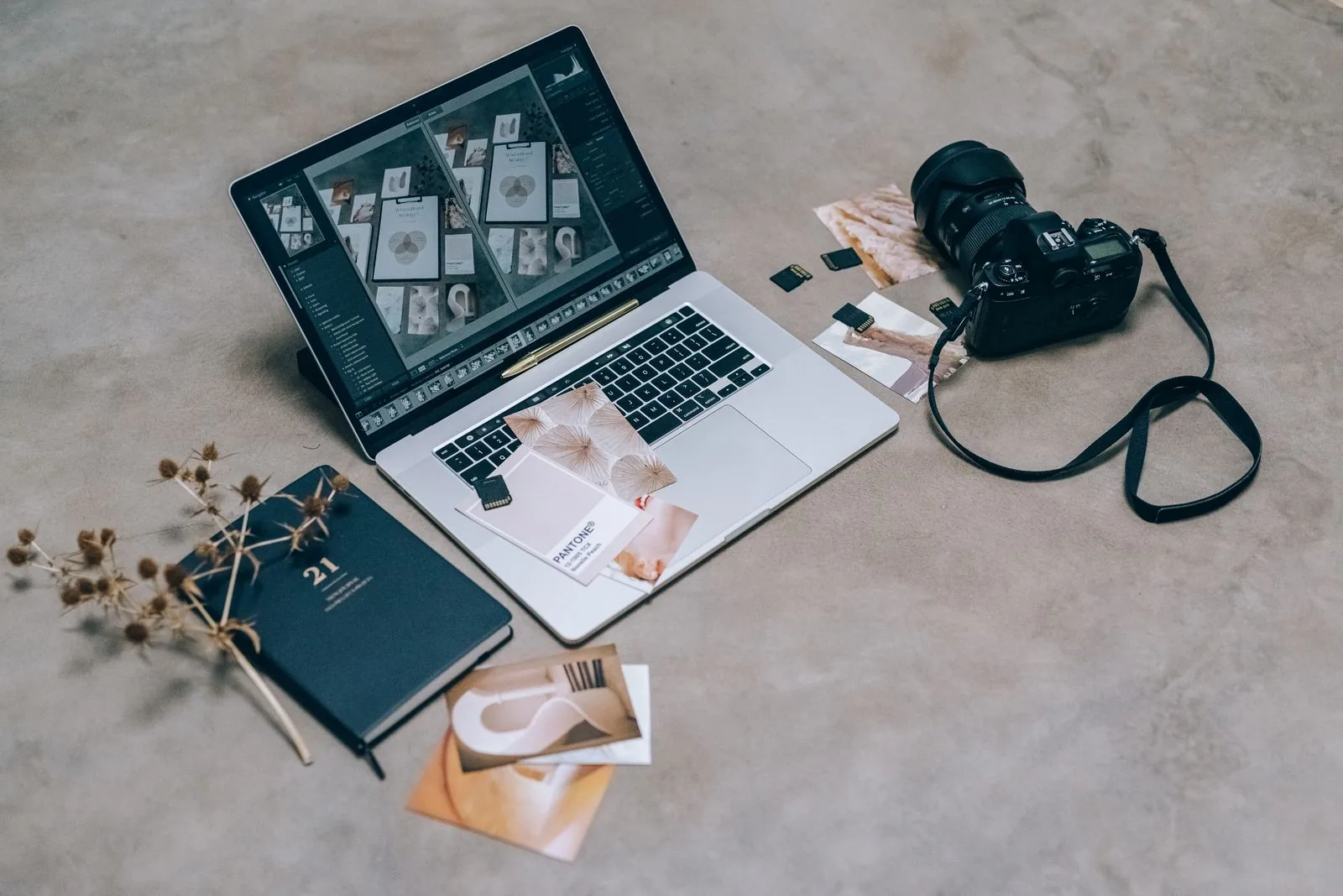 Vista dall'alto di uno spazio creativo con un laptop, una fotocamera e materiali di design, ideale per artisti digitali.