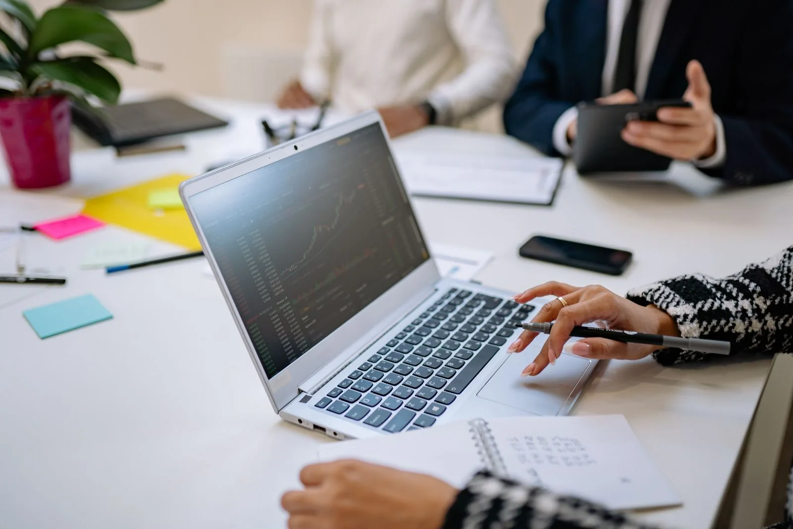 Professionisti analizzano dati finanziari su laptop durante una riunione in ufficio.